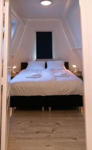 um quarto com uma cama grande com lençóis brancos e almofadas em 'T Heilige Pad em Egmond aan Zee