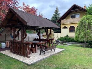 a wooden pavilion with a picnic table and a bench at JOKER Party House - Szigetszentmiklós in Szigetszentmiklós