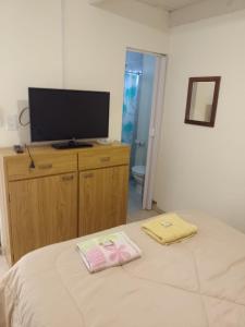 Dormitorio con cama y tocador con TV en El Ceibo en Carhué