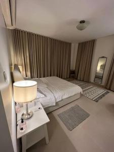 1 dormitorio con 1 cama y 1 mesa con lámpara en شقة الاحلام, en King Abdullah Economic City