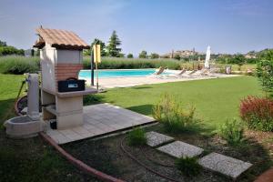 un patio trasero con barbacoa junto a la piscina en Villa Castiglioni, en Castiglion Fiorentino