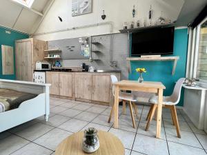 a kitchen with a table and a tv in a room at De ZeeuwSter in Burgh Haamstede