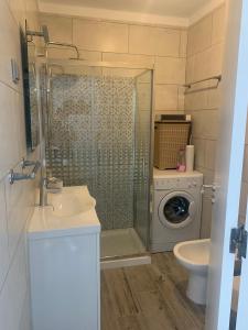 uma casa de banho com um chuveiro, um lavatório e uma máquina de lavar roupa em VAUMAR APARTMENT - SEA VIEW em Portimão