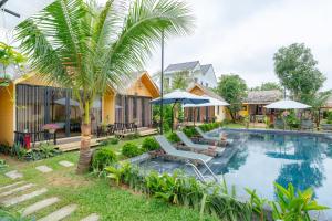 a villa with a swimming pool and a palm tree at Phoenix Hotel Pool Villa in Hoi An