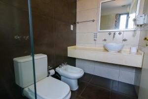 a bathroom with a toilet and a sink and a mirror at Hotel Coé Verá in Paraná