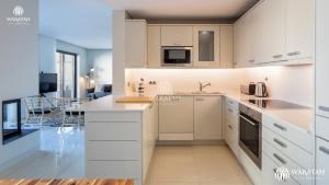 a kitchen with white cabinets and a living room at Apartment Micaela in Vale do Lobo