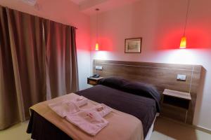 Una habitación con una cama con dos toallas rosas. en Hotel Coé Verá en Paraná