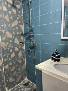 a blue tiled bathroom with a shower and a sink at CAB LFS SIPRES MOURTADA 3e ETAGE in Dakar