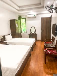 Habitación con 2 camas, silla y TV. en Khách sạn Lâm Viên, en Pho Mới