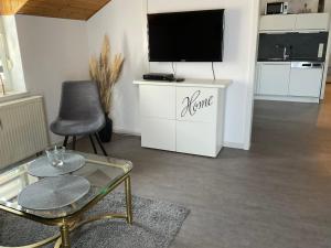 uma sala de estar com uma televisão, uma cadeira e uma mesa em Apartment Auszeit em Bad Neustadt an der Saale