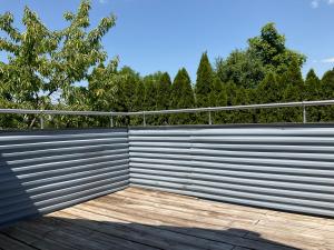 una valla de metal con una terraza de madera frente a los árboles en Apartment Auszeit, en Bad Neustadt an der Saale