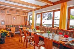 a restaurant with wooden tables and chairs and windows at Hotel Allgäu Garni in Scheidegg