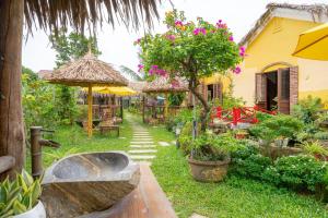 a garden with tables and umbrellas and a building at Phoenix Hotel Pool Villa in Hoi An