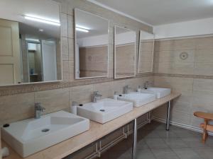 a bathroom with three sinks and two mirrors at Wood Cabins in the heart of Transylvania in Colţeşti