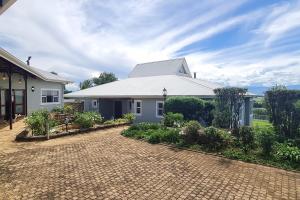 a large white house with a brick driveway at 25 Hazyview Drakensburg Mountain Views in Underberg