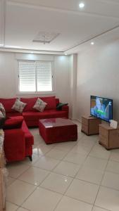 a living room with a red couch and a flat screen tv at Achakar in Tangier