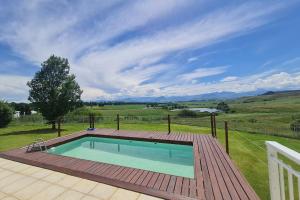 a swimming pool on a deck next to a fence at 25 Hazyview Drakensburg Mountain Views in Underberg