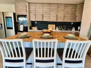 eine Küche mit einem Holztisch mit vier Stühlen und einem Tisch in der Unterkunft Hardangerfjord View - luxury fjord-side holiday home in Øystese