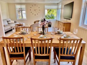 uma mesa de madeira com cadeiras e uma sala de jantar em Hardangerfjord View - luxury fjord-side holiday home em Øystese