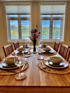 uma mesa de jantar com pratos e copos de vinho em Hardangerfjord View - luxury fjord-side holiday home em Øystese