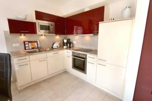 a small kitchen with white cabinets and appliances at Ferien_HAUS FOHLENWEIDE in Göhren-Lebbin +13 photos