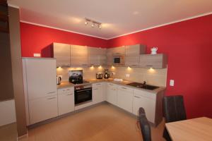 eine Küche mit weißen Schränken und einer roten Wand in der Unterkunft Ferienhaus CASA PRIMERA in Göhren-Lebbin