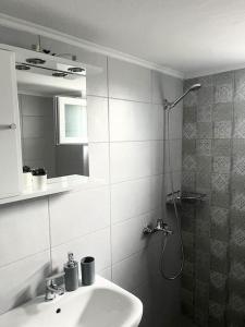 La salle de bains est pourvue d'un lavabo et d'une douche avec un miroir. dans l'établissement Eirini's House, à Paralia Dionisiou