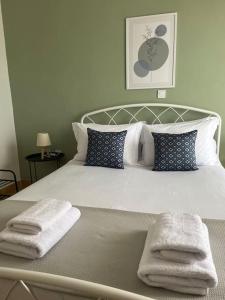 een wit bed met twee handdoeken erop bij Eirini's House in Paralia Dionysiou