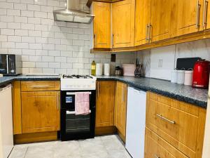 una cocina con armarios de madera y estufa negra en Family Home in Residential Neighbourhood en Cardiff