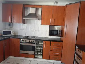 a kitchen with wooden cabinets and a stove and microwave at Sleepwell in East London