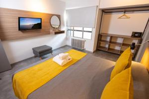 a bedroom with a yellow bed and a tv at HOTEL CONCEPT BARILOCHE in San Carlos de Bariloche