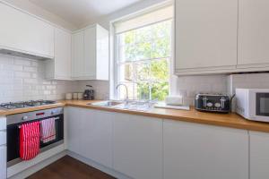 a kitchen with white cabinets and a sink and a window at Charming & Central 2BD Flat - Islington in London