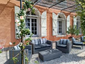 une terrasse avec des canapés et des chaises devant un bâtiment dans l'établissement Domaine de Roque Haute, à Portiragnes