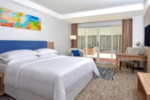 a bedroom with a large white bed and a desk at Four Points by Sheraton Makassar in Makassar