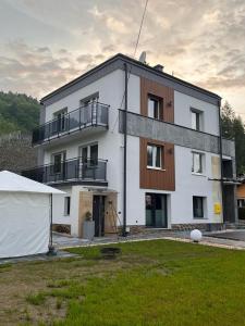 un gran edificio blanco con un patio delante en Apartament Muszyna, en Muszyna