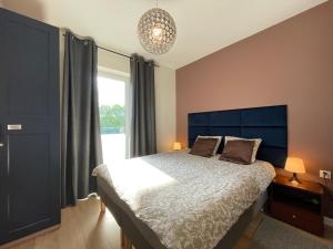 a bedroom with a bed with a blue headboard and a window at Superior Laguna 3 Rooms! Sauna&Gym! Air Condition! in Zarzecze
