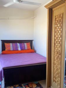 a bedroom with a bed with purple sheets and an orange pillow at الساحل الشمالي. قريه جراند هيلز الكيلو60 in Dawwār ‘Abd Allāh