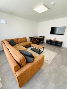 a living room with a brown couch and a table at Sehr schönes Haus mit Terasse nähe Düsseldorf in Krefeld