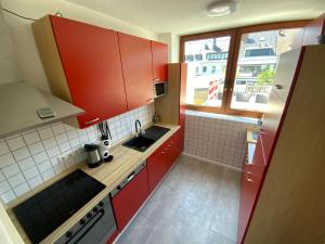 a small kitchen with red cabinets and a sink at Sehr schönes Haus mit Terasse nähe Düsseldorf in Krefeld