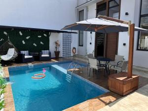 a swimming pool with a table and an umbrella at Villa da Serra 1 in Paraty