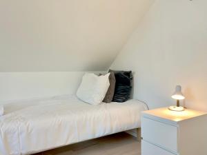 ギブにある2 Bedroom Apartment Located At Giveのベッド(白いシーツ、テーブルの上にランプ付)