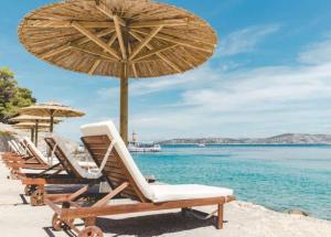 eine Gruppe von Stühlen und Sonnenschirmen am Strand in der Unterkunft Obonjan Island Resort in Šibenik