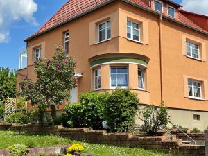 duży pomarańczowy dom z drzewem przed nim w obiekcie Apartment Wartenberg w mieście Eisenach