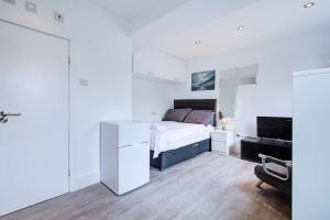 a white bedroom with a bed and a desk at Comfy and Convenient Studio Suite Lewisham with Free street parking, WIFI and quick access to central London Sleep 3 in Forest Hill