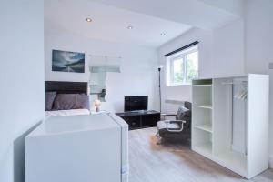 a white room with a bed and a couch at Comfy and Convenient Studio Suite Lewisham with Free street parking, WIFI and quick access to central London Sleep 3 in Forest Hill