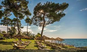 a row of lounge chairs and umbrellas on a beach at Cardo Apartments in Poreč