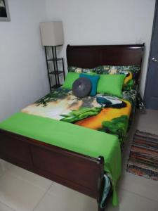 a bed with a green comforter with a bird on it at Fruta mango 1 in Orotina