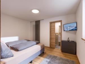- une chambre avec un lit et une télévision murale dans l'établissement Haus Brixenbach, à Brixen im Thale
