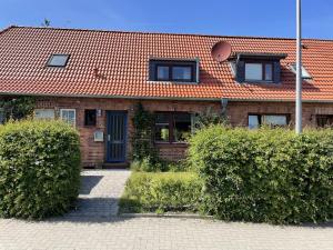 a brick house with a red roof and some bushes at Ferienhaus Jenny in Flensburg
