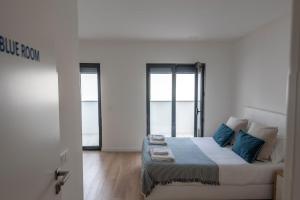 a white room with a bed and two windows at Beach & Sea Guesthouse in Espinho